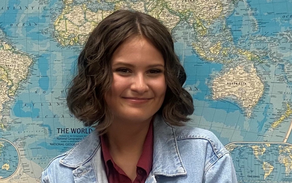 Angel Cramer smiles in front of a world map.